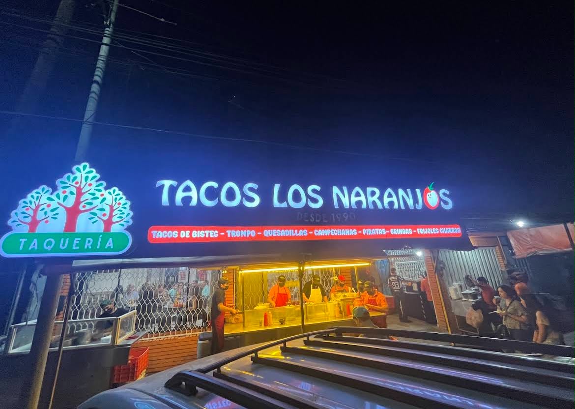 Fachada iluminada de Tacos Los Naranjos de noche en Monterrey